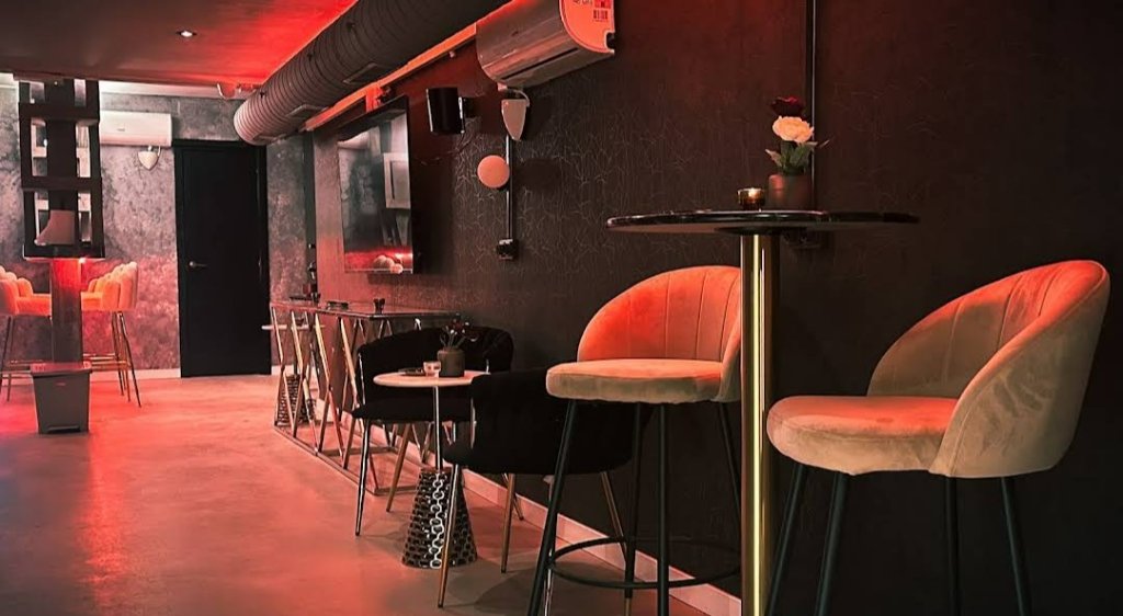 Interior del club Rolling Stoned en Barcelona con mesas altas, sillas y luz ambiental roja